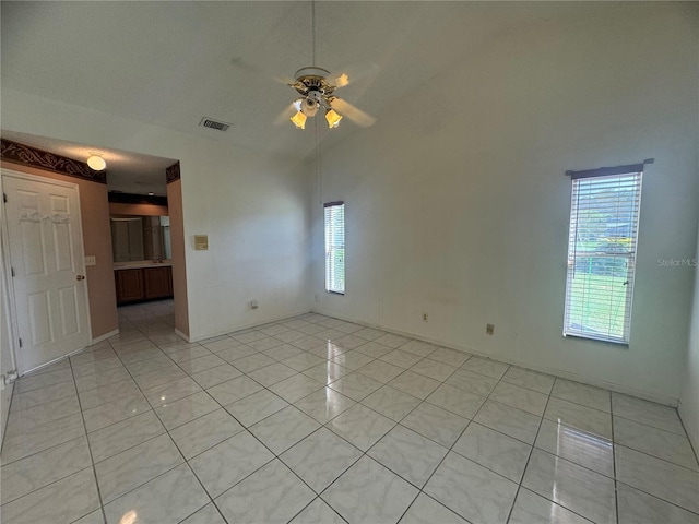 tiled spare room featuring ceiling fan and vaulted ceiling