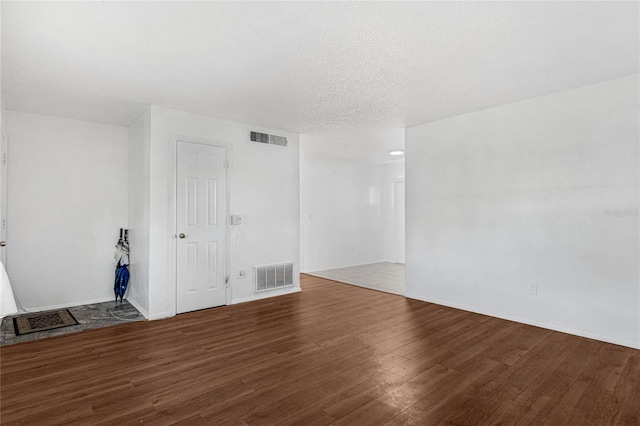 spare room featuring a textured ceiling and dark wood-type flooring