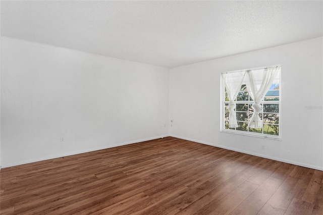 empty room with a textured ceiling and dark hardwood / wood-style flooring