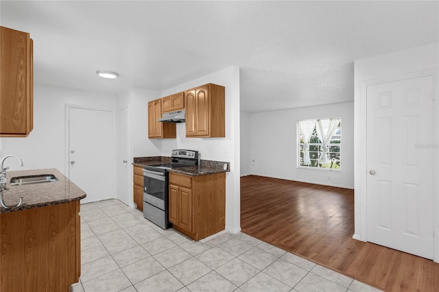 2319 Continental Blvd, Orlando, FL 32808 - kitchen with stainless steel range with electric cooktop, a sink, dark stone countertops, light tile patterned floors, and under cabinet range hood