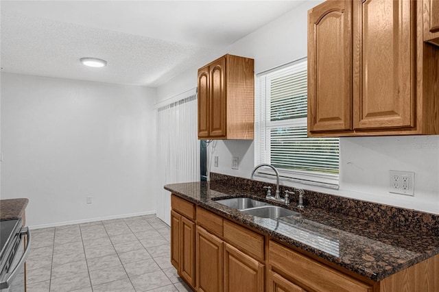 kitchen featuring stainless steel electric range, sink, dark stone counters, and a wealth of natural light