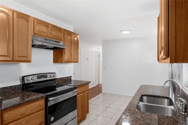 kitchen featuring stainless steel electric stove, light tile patterned floors, sink, and dark stone counters