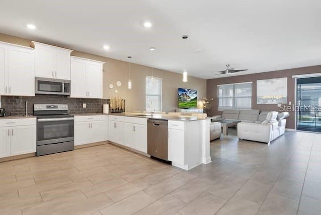 kitchen with a healthy amount of sunlight, stainless steel appliances, white cabinetry, and kitchen peninsula