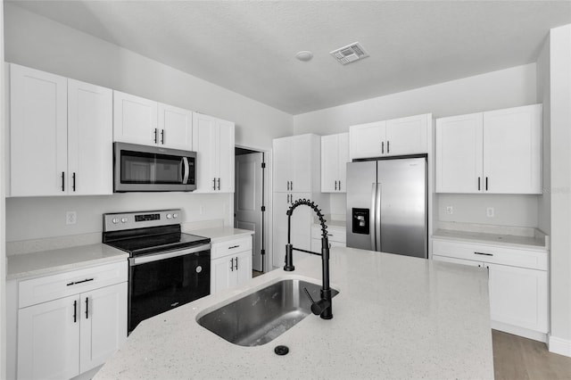 kitchen with white cabinetry, light stone counters, and stainless steel appliances