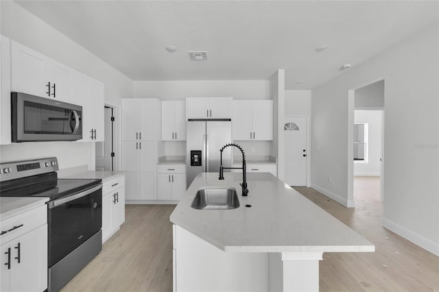 kitchen with sink, stainless steel appliances, white cabinets, light hardwood / wood-style flooring, and a center island with sink