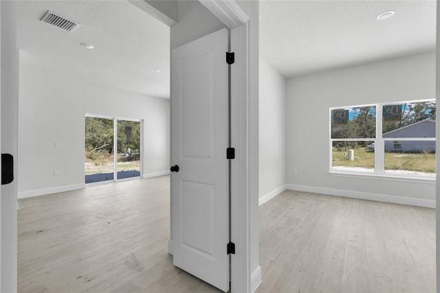 corridor with a wealth of natural light and light hardwood / wood-style flooring