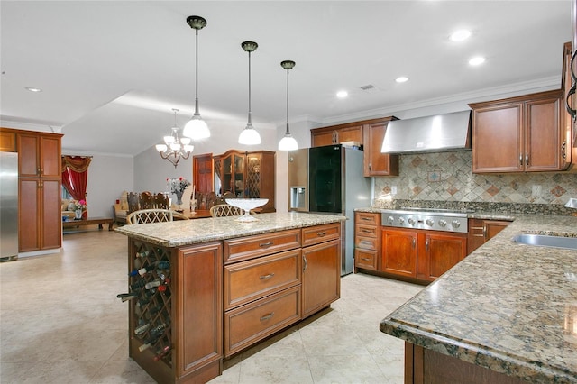 kitchen featuring stainless steel appliances, wall chimney range hood, pendant lighting, a chandelier, and a center island