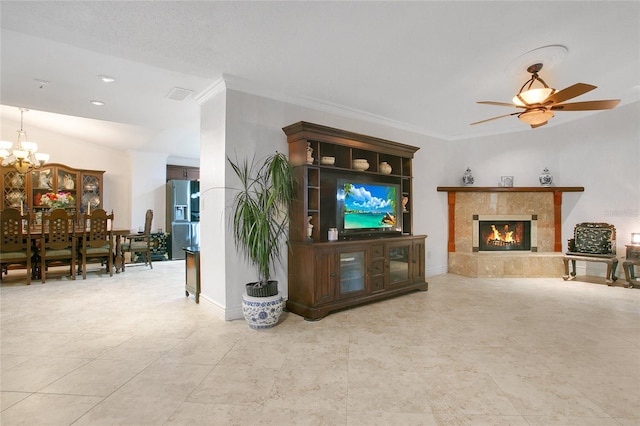 living room featuring a fireplace, ceiling fan with notable chandelier, light tile patterned floors, and ornamental molding