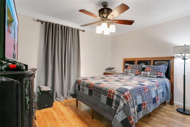 bedroom with light hardwood / wood-style floors, ceiling fan, and crown molding