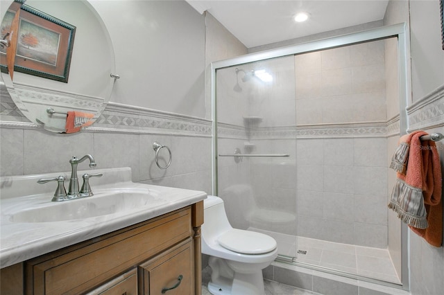 bathroom with tile patterned floors, toilet, tile walls, an enclosed shower, and vanity