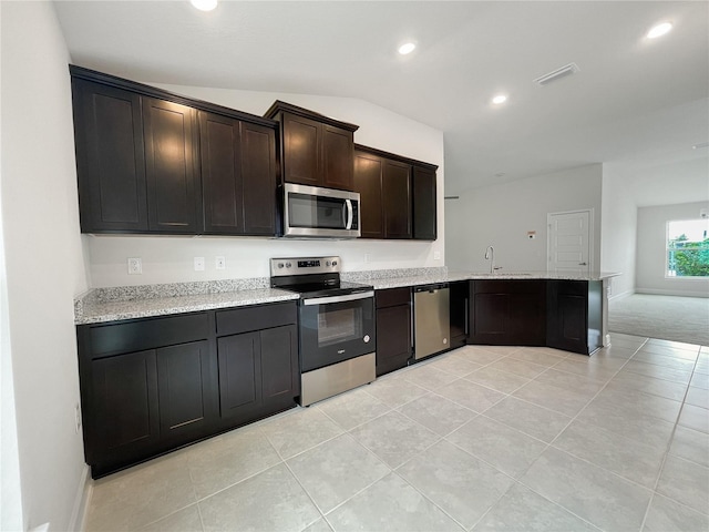 kitchen featuring light tile patterned floors, light stone countertops, vaulted ceiling, sink, and stainless steel appliances