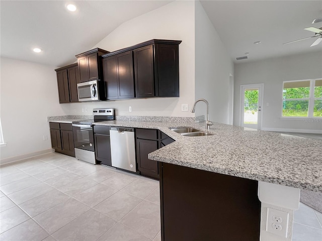 kitchen with lofted ceiling, sink, appliances with stainless steel finishes, and kitchen peninsula