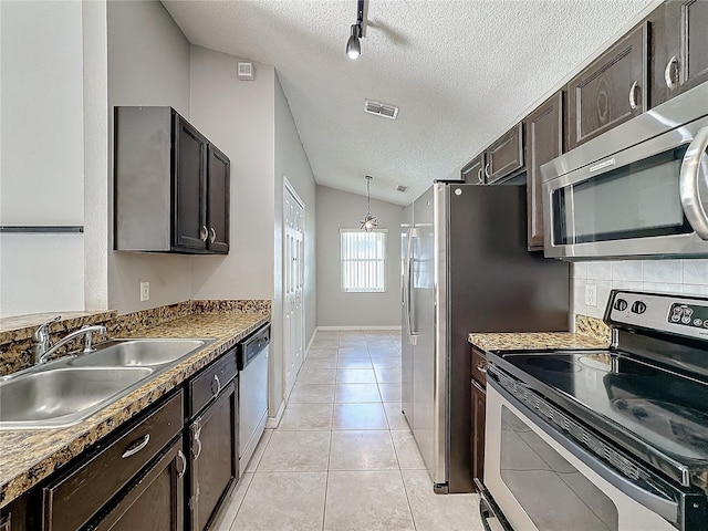 kitchen with a textured ceiling, stainless steel appliances, sink, lofted ceiling, and light tile patterned flooring