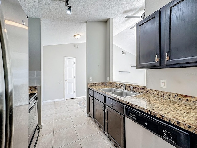 kitchen featuring a textured ceiling, stainless steel appliances, vaulted ceiling, sink, and light tile patterned floors