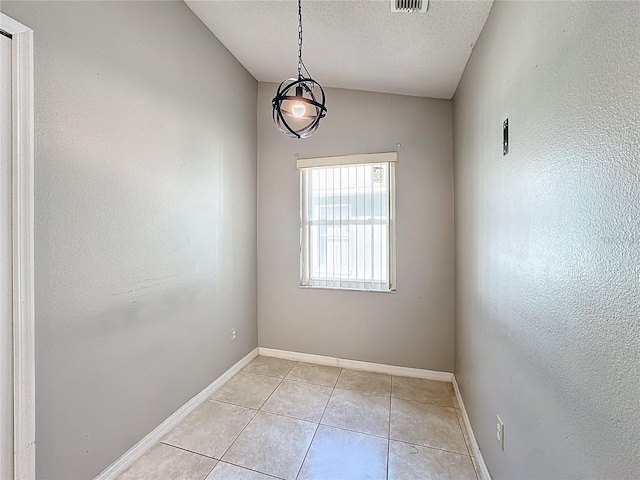 tiled spare room featuring a textured ceiling and lofted ceiling