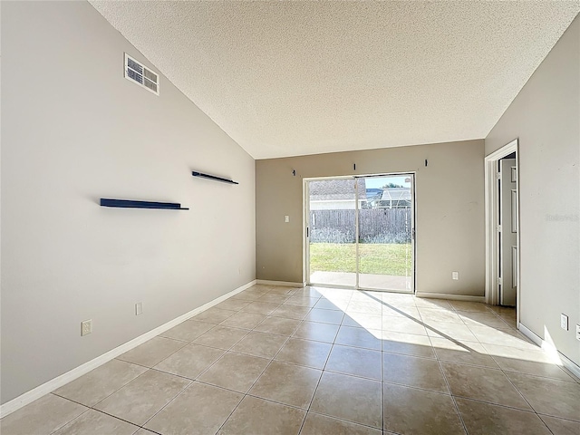 tiled spare room featuring a textured ceiling and vaulted ceiling