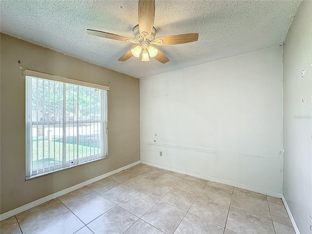 unfurnished room with ceiling fan, light tile patterned floors, and a textured ceiling