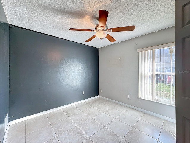 empty room with ceiling fan, light tile patterned floors, and a textured ceiling