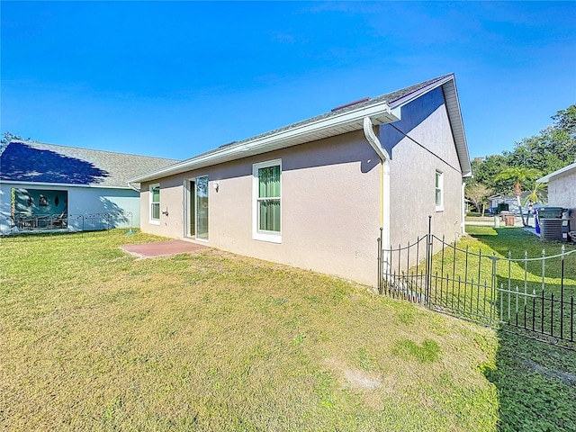 back of property with a lawn, central air condition unit, and a patio