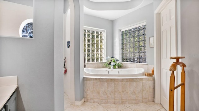 bathroom with vanity, a relaxing tiled tub, and tile patterned flooring