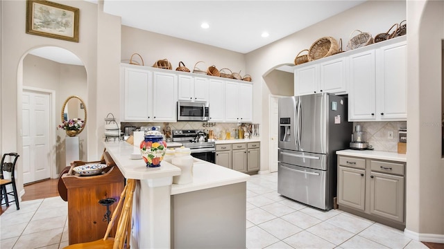 kitchen with backsplash, appliances with stainless steel finishes, kitchen peninsula, and white cabinets