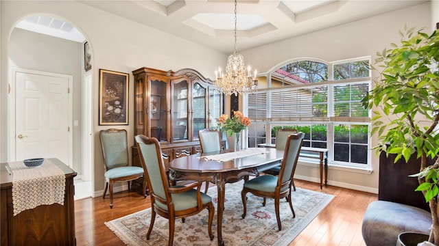 dining space with coffered ceiling, beam ceiling, hardwood / wood-style flooring, and a chandelier