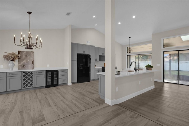 kitchen with vaulted ceiling, gray cabinetry, beverage cooler, and black fridge with ice dispenser