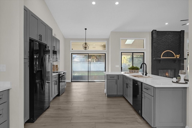 kitchen with vaulted ceiling, light hardwood / wood-style flooring, black appliances, gray cabinets, and sink