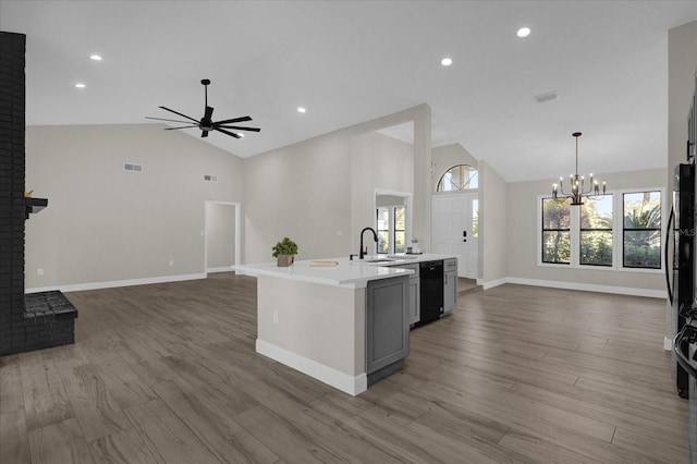 kitchen featuring hanging light fixtures, a center island with sink, high vaulted ceiling, wood-type flooring, and a fireplace