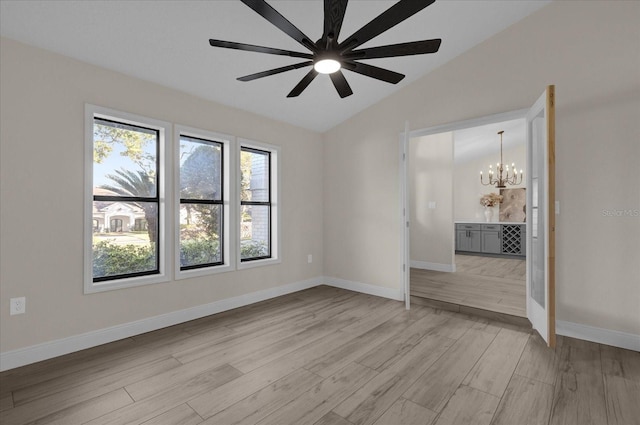 unfurnished room featuring light hardwood / wood-style flooring, lofted ceiling, and ceiling fan with notable chandelier