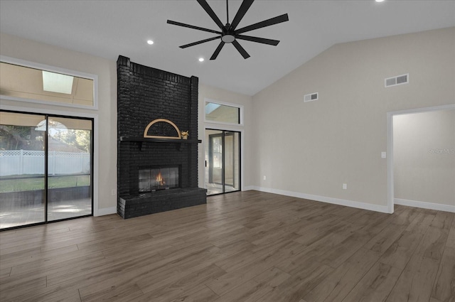 unfurnished living room with ceiling fan, hardwood / wood-style flooring, high vaulted ceiling, and a brick fireplace