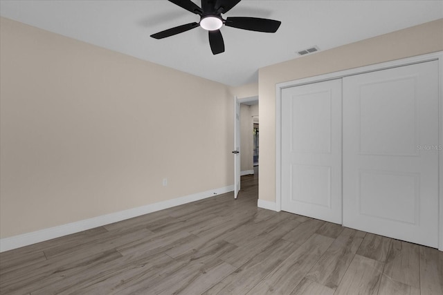 unfurnished bedroom featuring a closet, light hardwood / wood-style floors, and ceiling fan