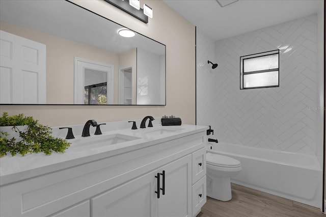 full bathroom with toilet, tiled shower / bath, hardwood / wood-style flooring, and vanity