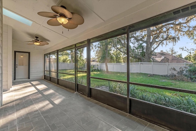 unfurnished sunroom featuring ceiling fan and a skylight