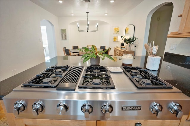 kitchen with pendant lighting, stainless steel gas cooktop, light brown cabinetry, and a chandelier