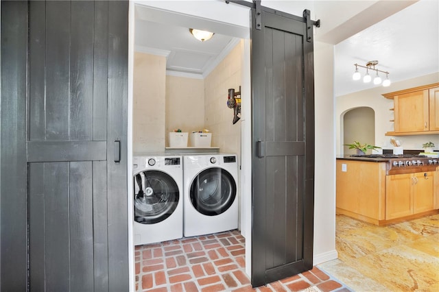 clothes washing area with washer and dryer, a barn door, and crown molding