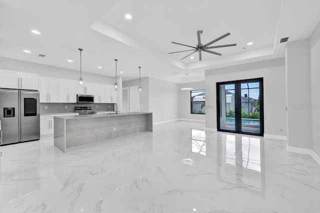 kitchen with pendant lighting, french doors, white cabinets, a raised ceiling, and stainless steel appliances