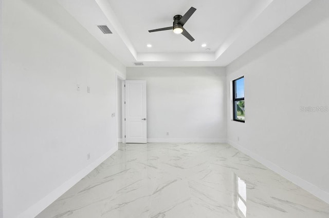 empty room featuring a tray ceiling and ceiling fan