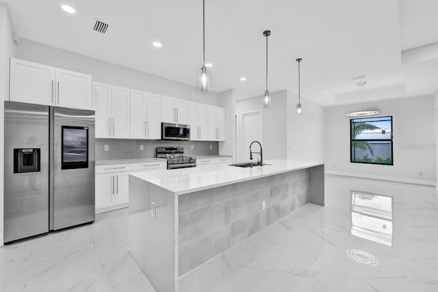 kitchen featuring appliances with stainless steel finishes, white cabinetry, a kitchen island with sink, and pendant lighting