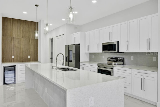 kitchen with a large island with sink, white cabinetry, hanging light fixtures, and appliances with stainless steel finishes