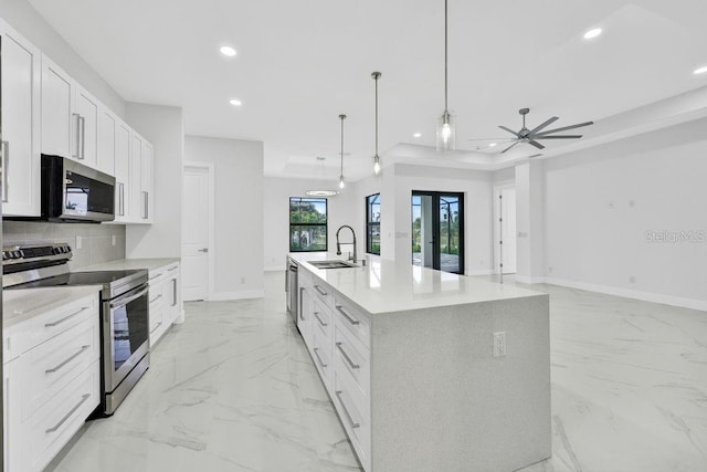 kitchen with white cabinets, hanging light fixtures, stainless steel appliances, and a kitchen island with sink