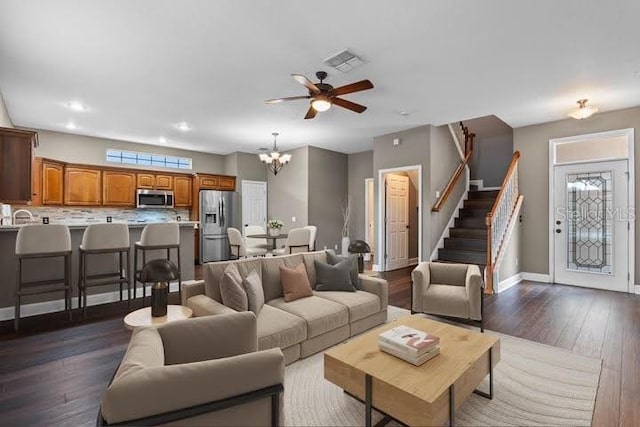 living room featuring ceiling fan with notable chandelier and dark hardwood / wood-style flooring