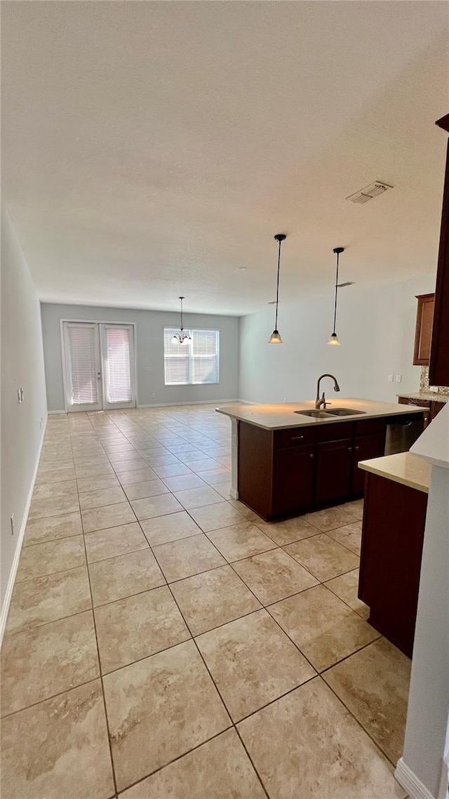 kitchen with light tile patterned floors, dark brown cabinets, sink, and hanging light fixtures