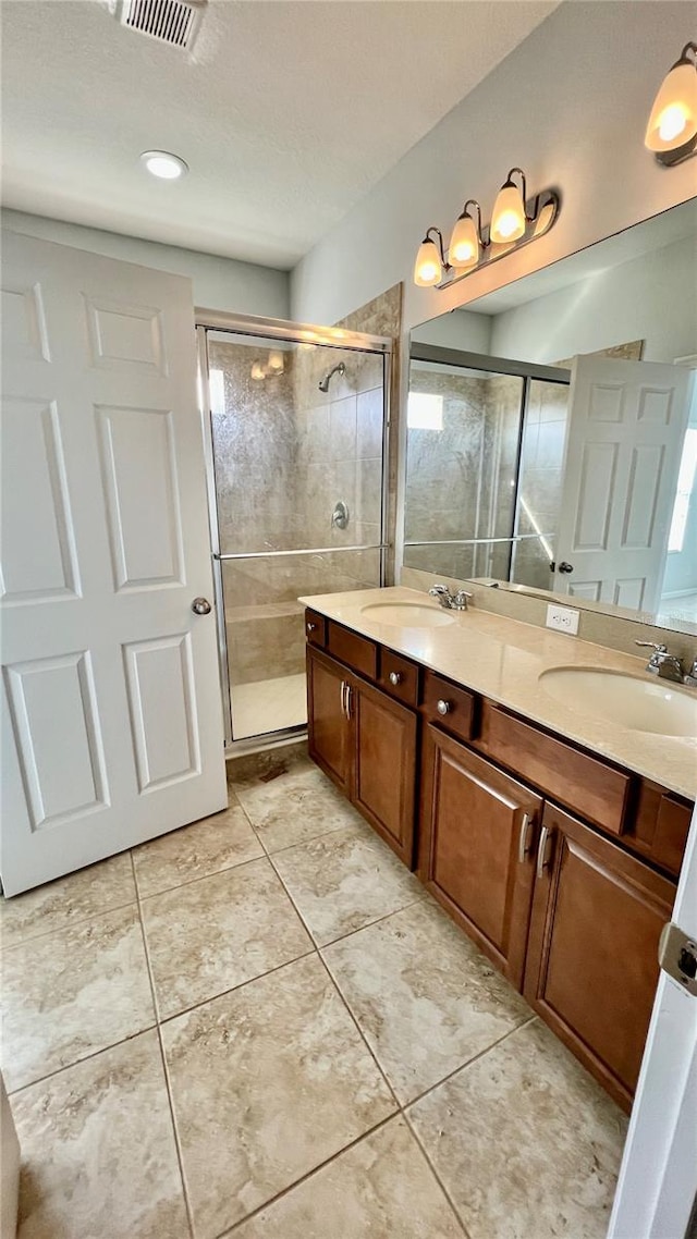 bathroom featuring a shower with door, vanity, a textured ceiling, and tile patterned flooring