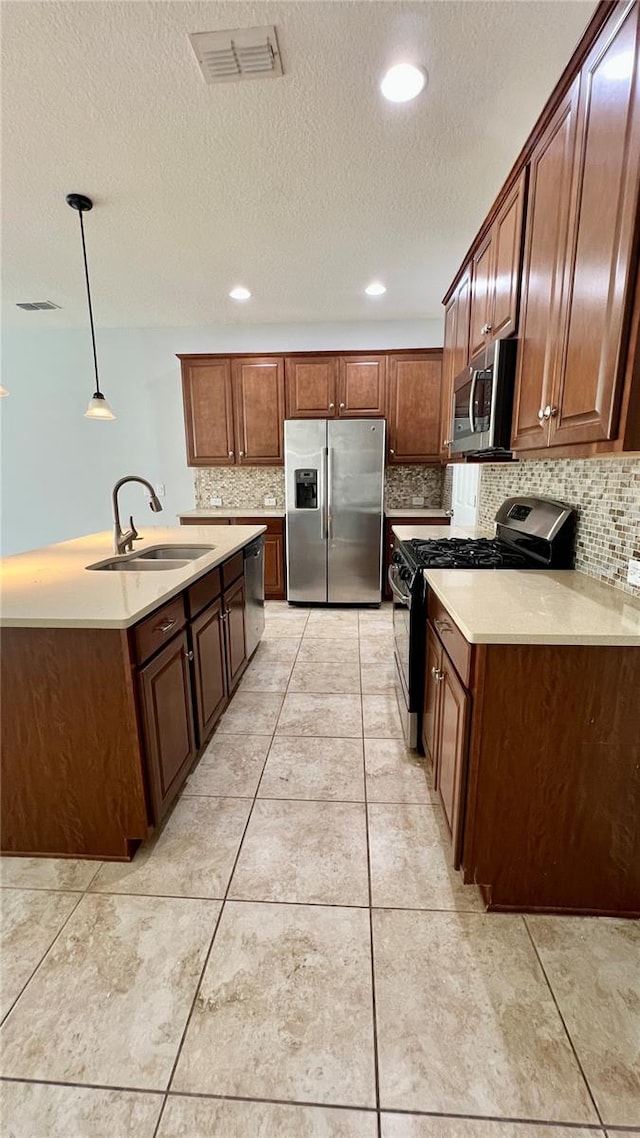 kitchen featuring tasteful backsplash, appliances with stainless steel finishes, a textured ceiling, sink, and decorative light fixtures