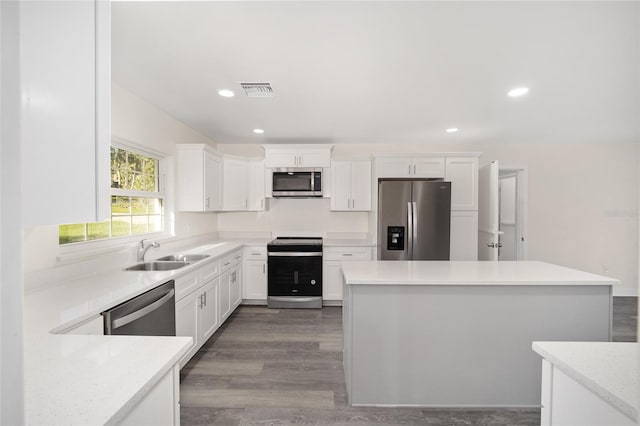 kitchen with white cabinets, stainless steel appliances, wood-type flooring, and sink