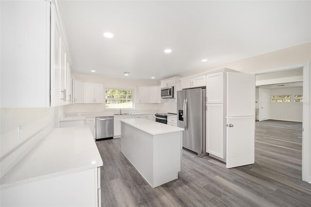 kitchen featuring dark hardwood / wood-style flooring, appliances with stainless steel finishes, a center island, and white cabinets