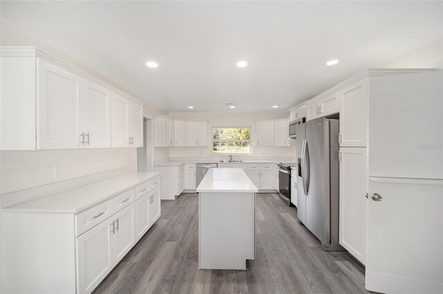 kitchen featuring a center island, white cabinets, stainless steel appliances, and wood-type flooring