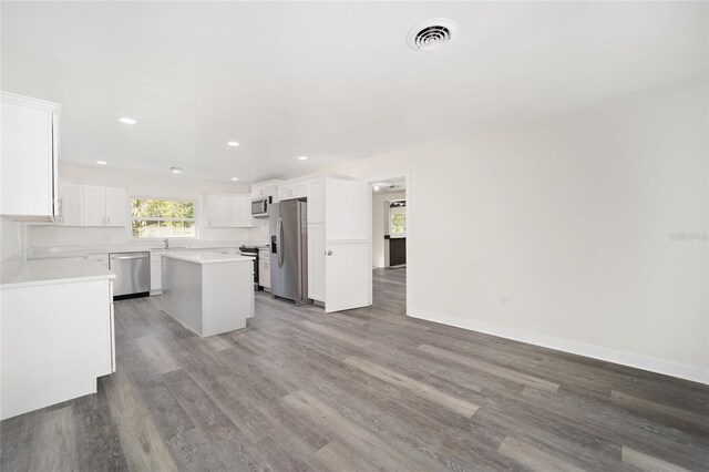 kitchen with appliances with stainless steel finishes, sink, wood-type flooring, a center island, and white cabinetry