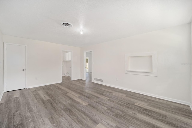 empty room with a textured ceiling and wood-type flooring